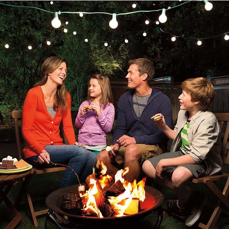 family making and enjoying outdoor campfire smores at night